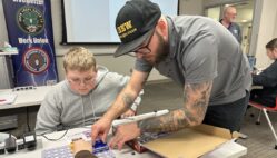 Riley Waters helps a student assemble an electrical circuit board Dec. 19, 2024, after giving a presentation on how students can become electricians through the local IBEW union at Southeastern Community College during its annual 8th Grade Career Fair in West Burlington.